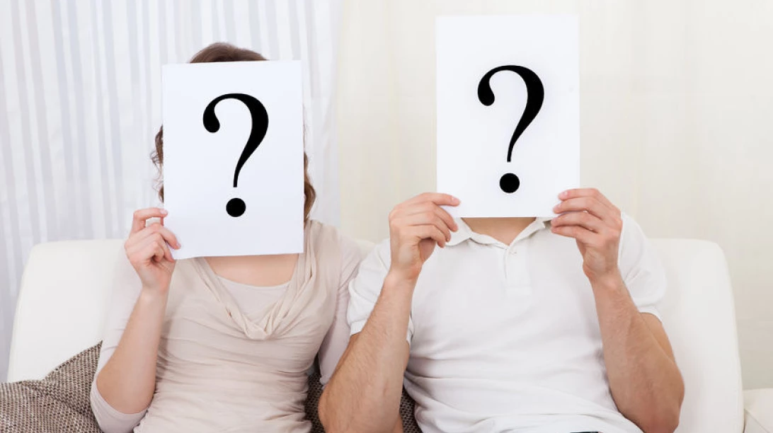 Couple cachant leurs visages avec un point d'interrogation.