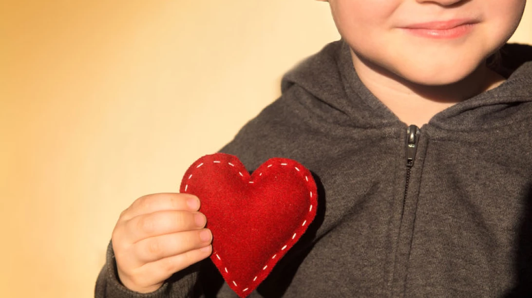 Enfant tenant un coeur symbolisant l'amour qu'il a pour lui.