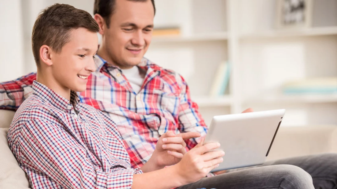 Photo d'un homme et son fils observant une tablette.