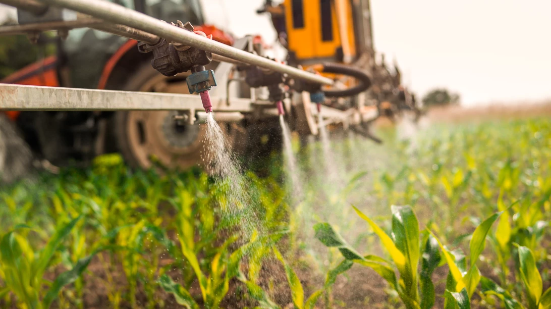 Tracteur en train d'arroser un champ de pesticides.
