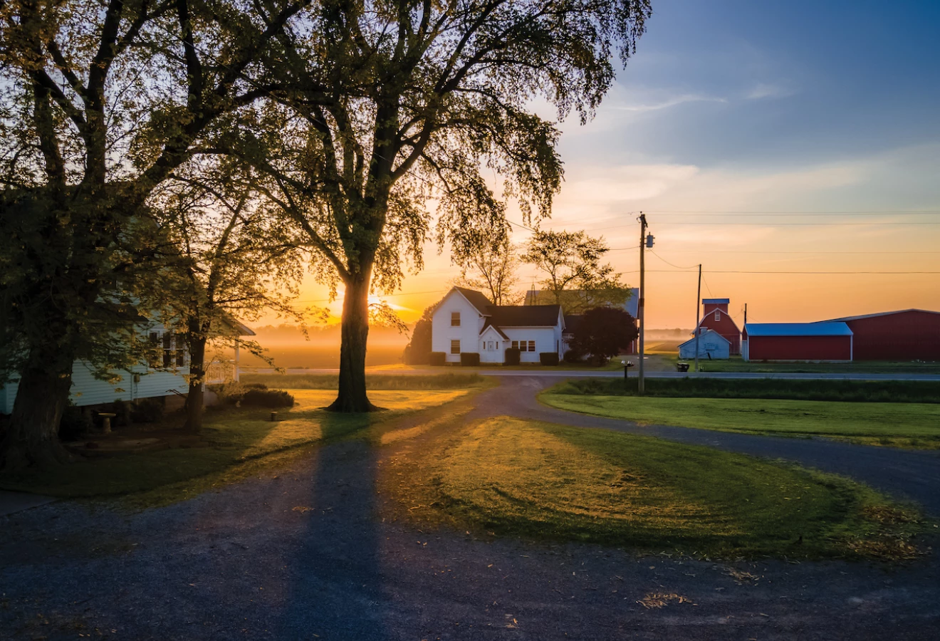 Maison sur une terre agricole, sur fond de coucher de soleil