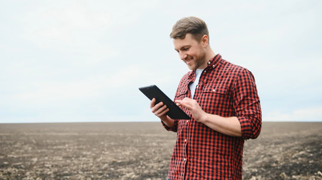 Homme dans un champ avec sa tablette.