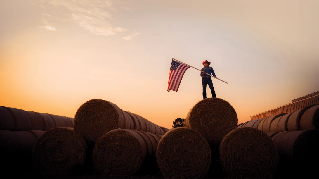 Femme tenant drapeau américain sur balles de foin