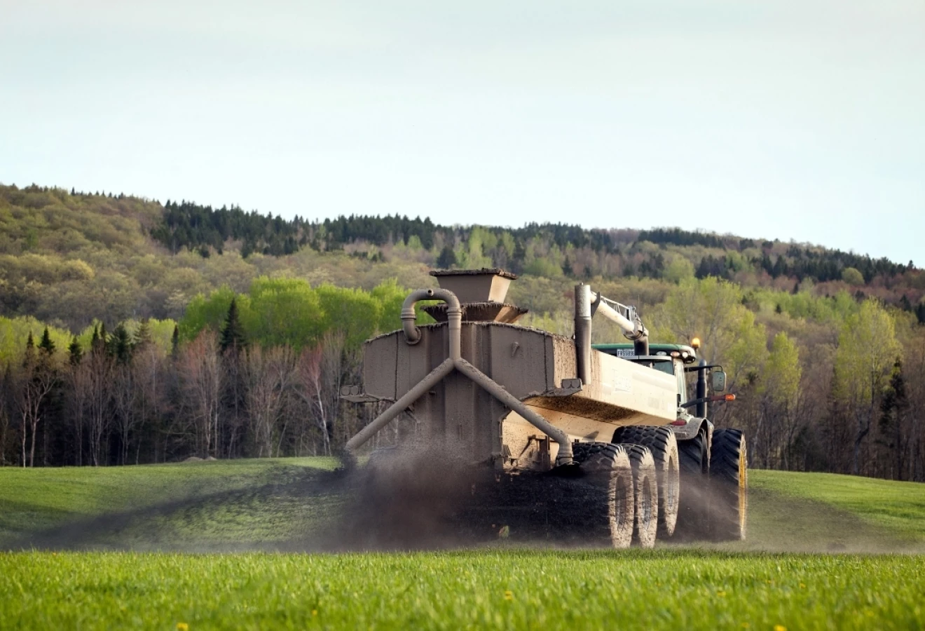 Une citerne épand du fumier dans un champ agricole.