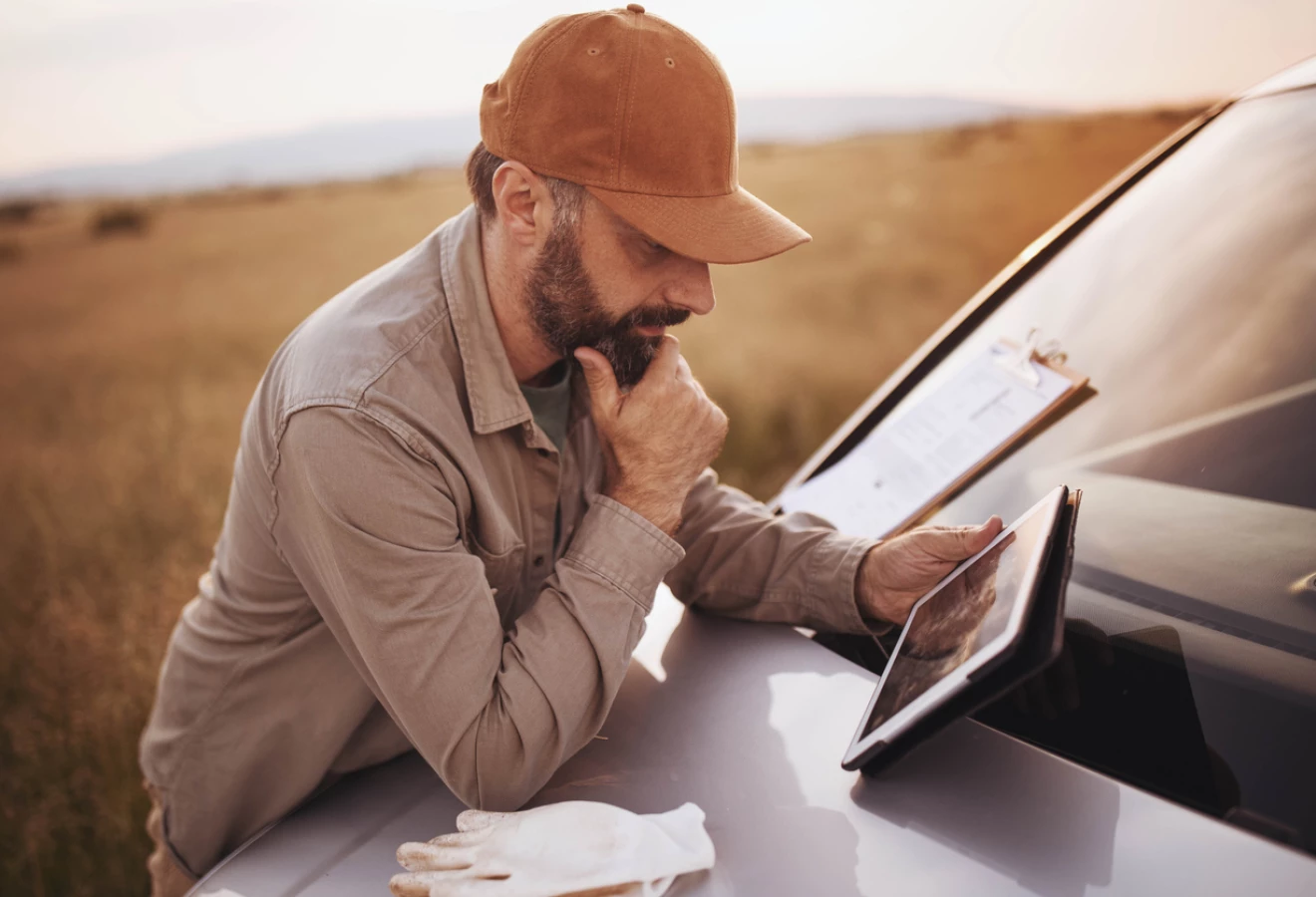 Homme observant sa tablette sur le pare-choc d'un camion.