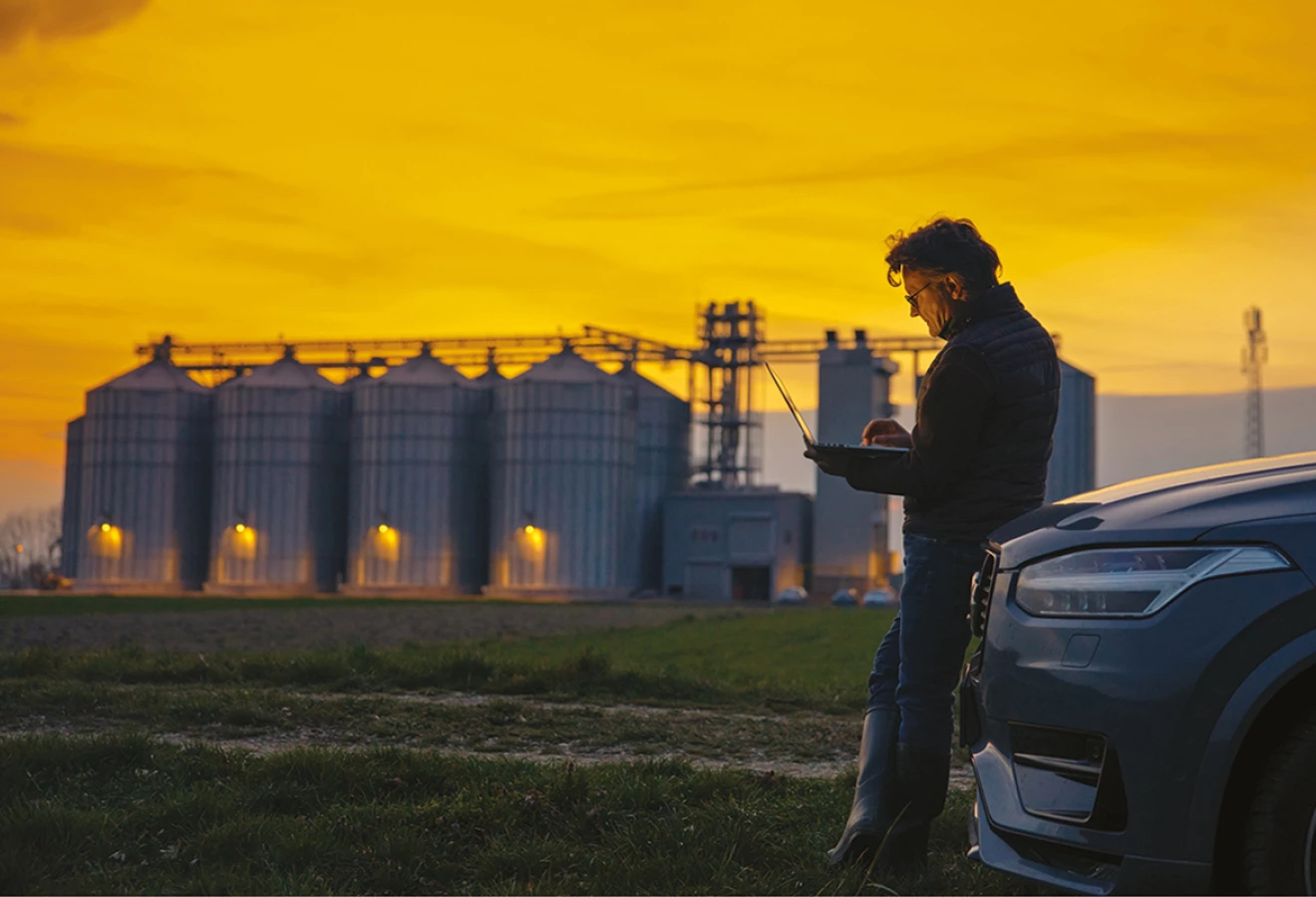 Homme utilisant une tablette devant des silos le matin