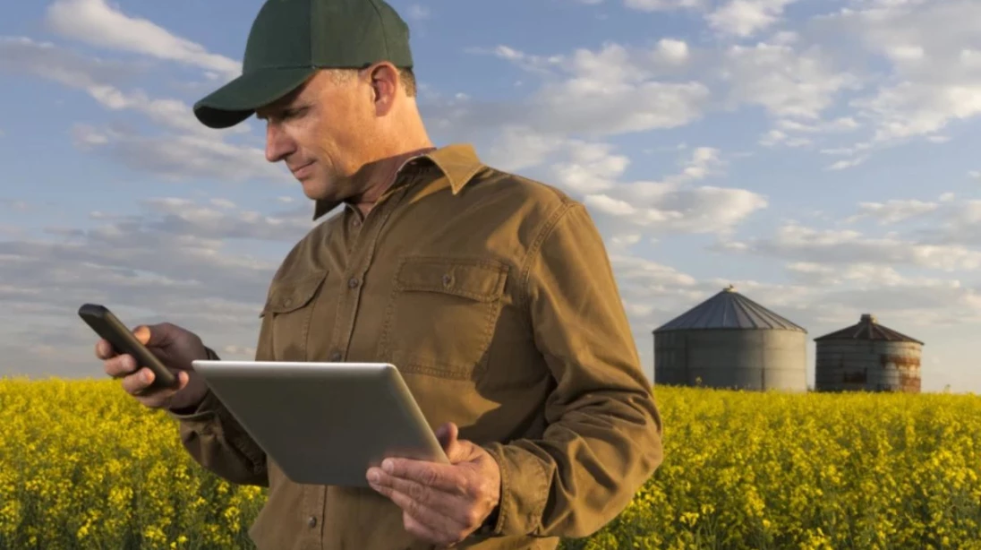 Homme dans un champ avec une tablette et un téléphone