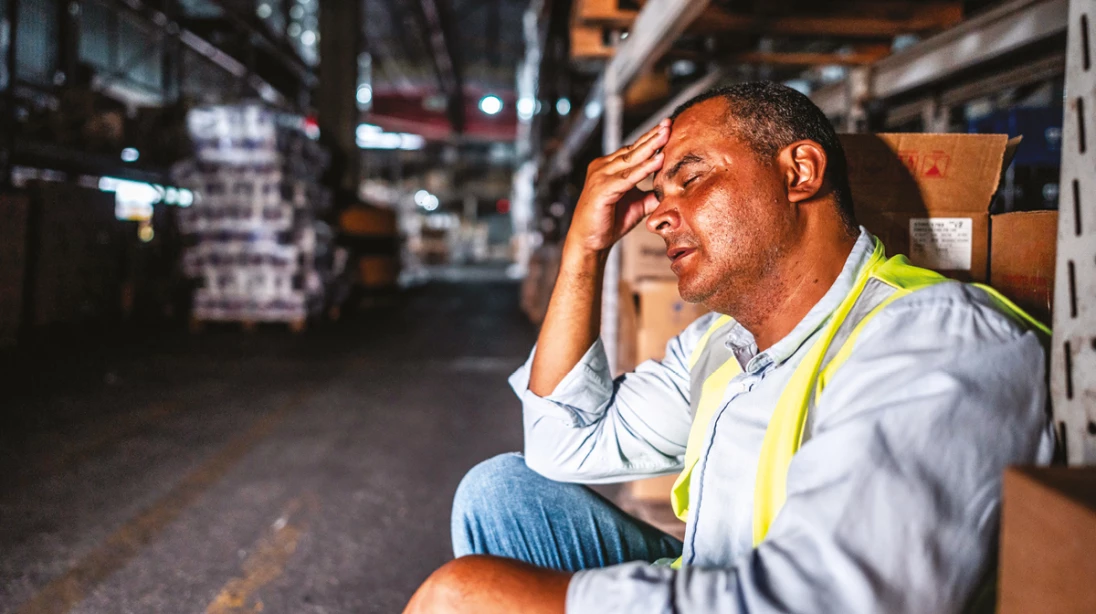 Homme épuisé assis dans un entrepôt