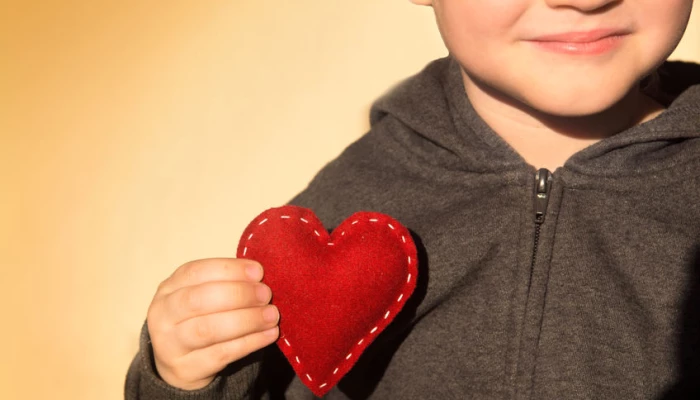Enfant tenant un coeur symbolisant l'amour qu'il a pour lui.