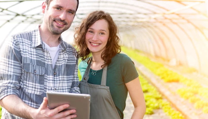Homme et femme dans une serre avec une tablette à la main.