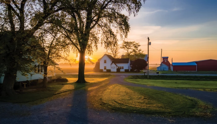 Maison sur une terre agricole, sur fond de coucher de soleil