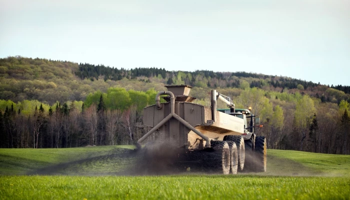 Une citerne épand du fumier dans un champ agricole.