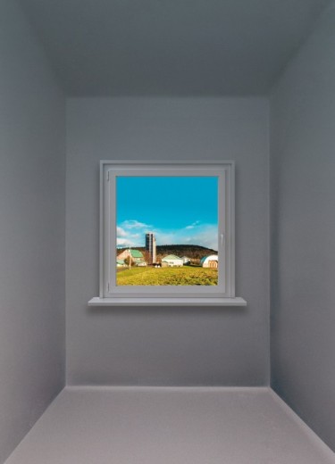 Pièce grise où on voit une fenêtre qui donne sur une ferme idyllique